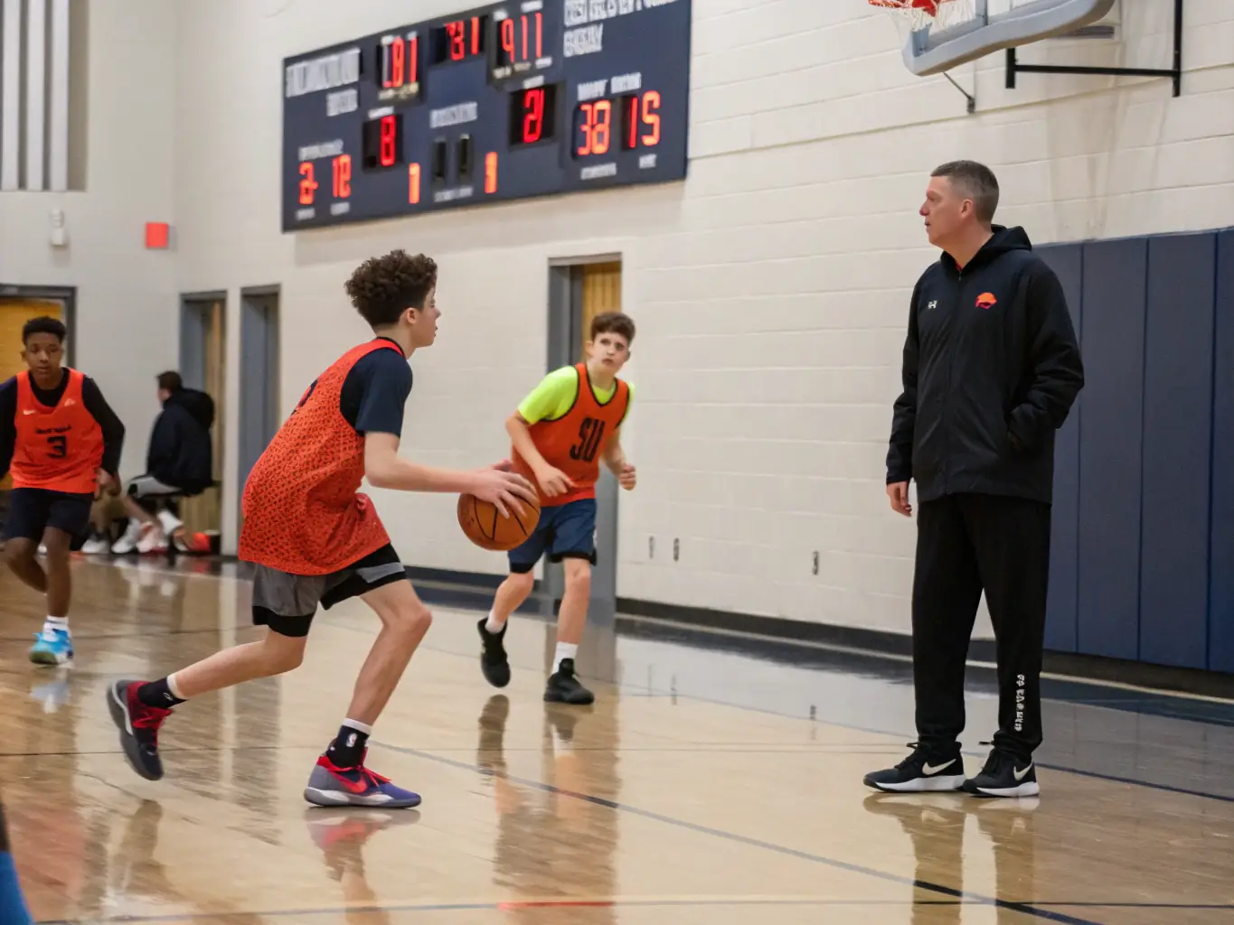 An action shot of teenagers playing basketball in an indoor court, showcasing teamwork and competitive spirit.